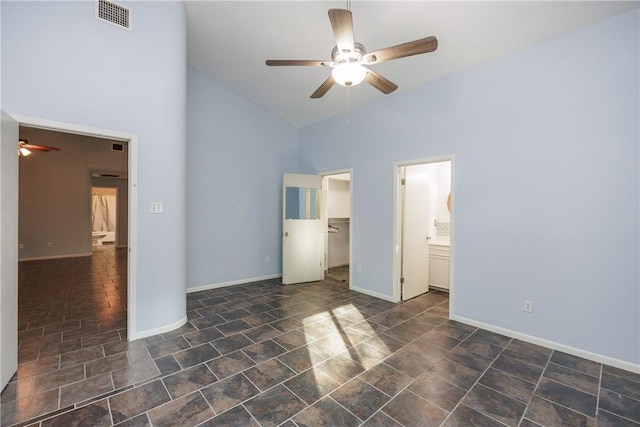 unfurnished bedroom featuring ceiling fan, a spacious closet, connected bathroom, high vaulted ceiling, and a closet