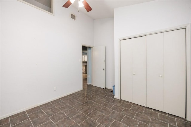 unfurnished bedroom featuring ceiling fan, a closet, and a high ceiling