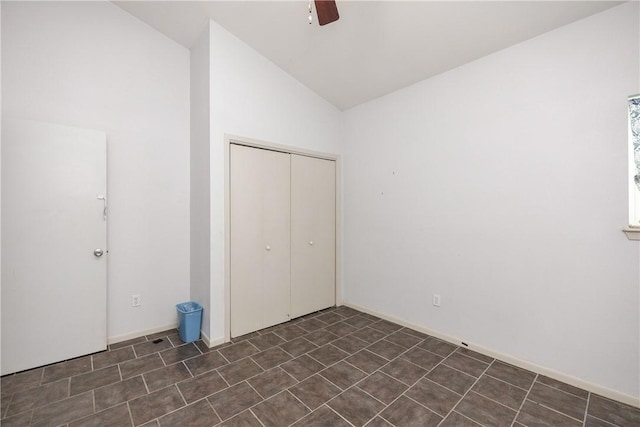 unfurnished bedroom with ceiling fan, a closet, and lofted ceiling