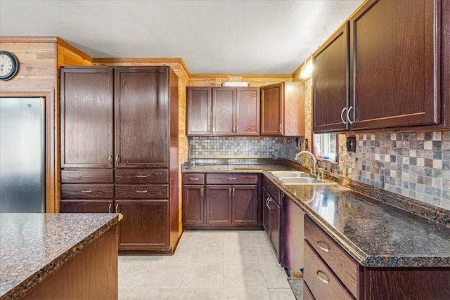 kitchen featuring light tile patterned flooring, dark stone countertops, sink, and tasteful backsplash