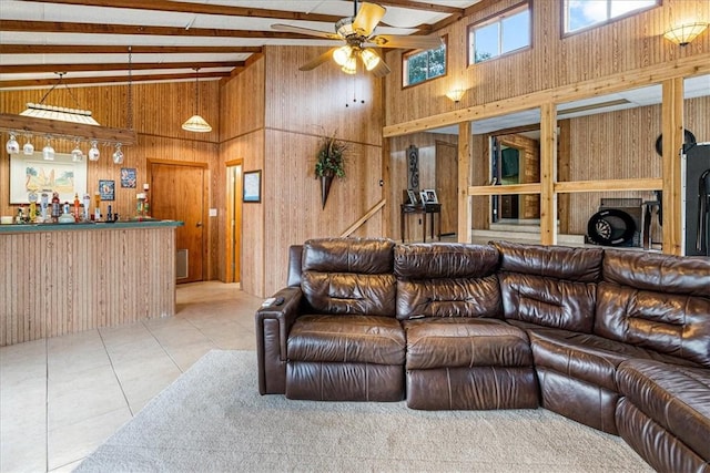 tiled living room with beam ceiling, bar area, wood walls, and high vaulted ceiling