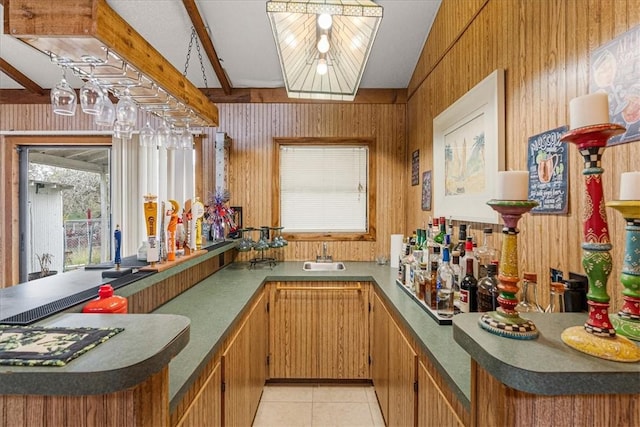 kitchen with light tile patterned floors, sink, beam ceiling, and wood walls