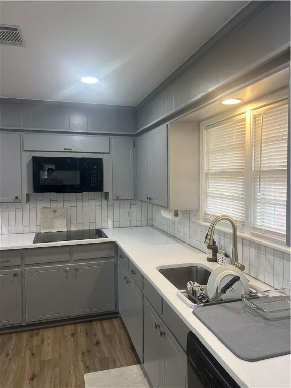 3023 66th St, Lubbock, TX 79413 - kitchen featuring gray cabinetry, black appliances, a sink, and tasteful backsplash