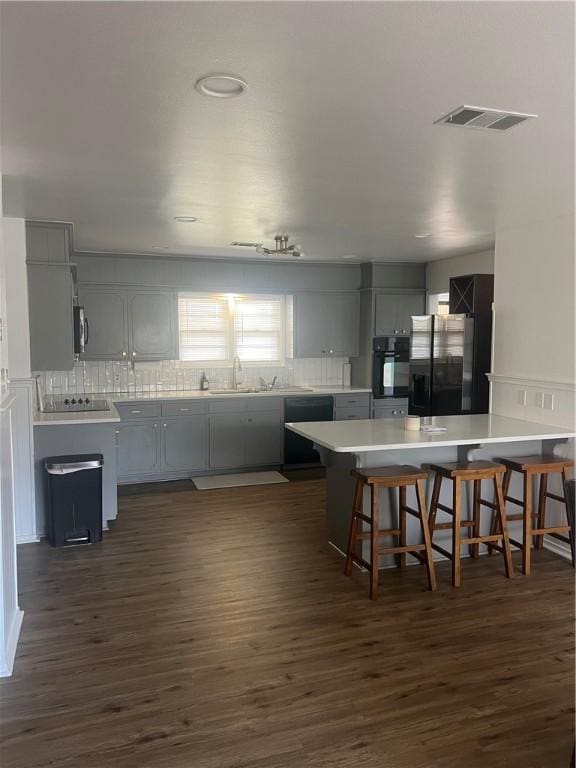3023 66th St, Lubbock, TX 79413 - kitchen with black appliances, dark wood-type flooring, a peninsula, and gray cabinets