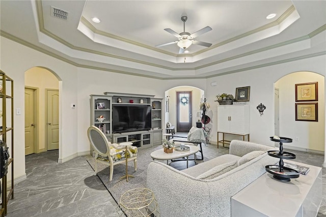 living room featuring ceiling fan, ornamental molding, and a tray ceiling