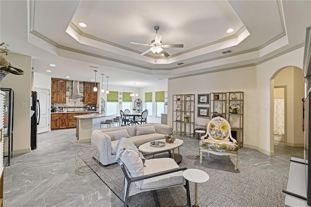 living room with ceiling fan, ornamental molding, and a tray ceiling