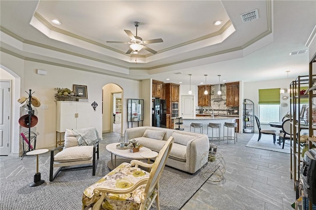 living room featuring a tray ceiling, ornamental molding, and ceiling fan