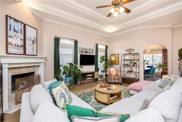 living room with hardwood / wood-style floors, ceiling fan, ornamental molding, and a tiled fireplace