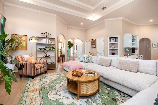 living room with crown molding, a towering ceiling, and wood-type flooring