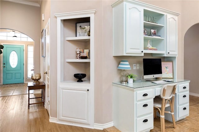 office space featuring crown molding, a wealth of natural light, light hardwood / wood-style flooring, and built in desk