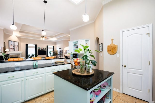 kitchen featuring dark stone counters, ceiling fan, light tile patterned floors, decorative light fixtures, and a kitchen island