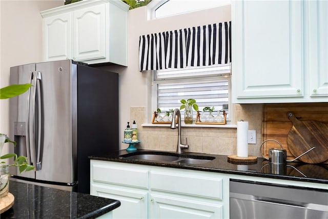 kitchen with backsplash, stainless steel appliances, sink, dark stone countertops, and white cabinets