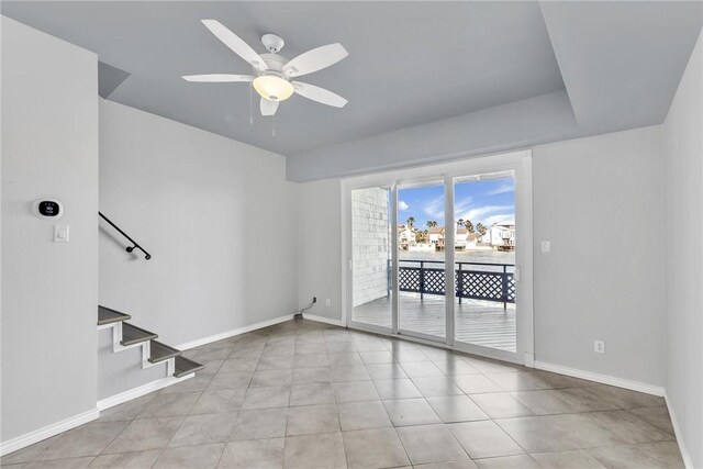 unfurnished room with light tile patterned floors, baseboards, ceiling fan, and stairs