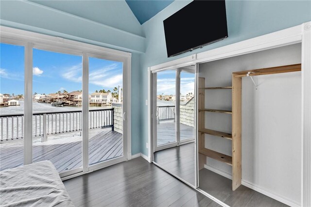 unfurnished bedroom featuring baseboards, wood finished floors, lofted ceiling, and access to outside