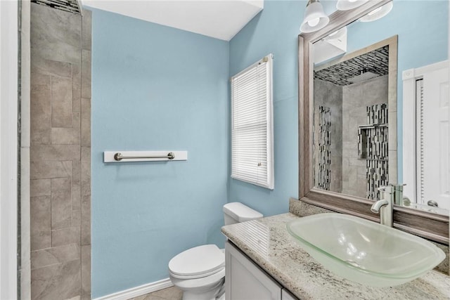 full bathroom with baseboards, toilet, vanity, and a tile shower