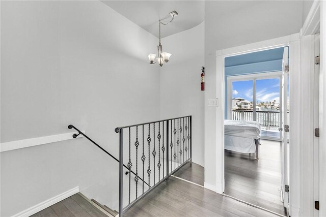 stairs featuring a notable chandelier, wood finished floors, and baseboards