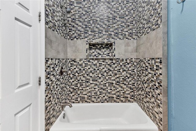 bathroom with shower / washtub combination and a textured wall