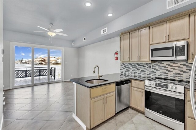 kitchen featuring visible vents, a sink, appliances with stainless steel finishes, a peninsula, and decorative backsplash