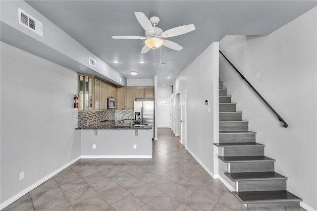 kitchen featuring visible vents, stainless steel appliances, decorative backsplash, glass insert cabinets, and dark countertops