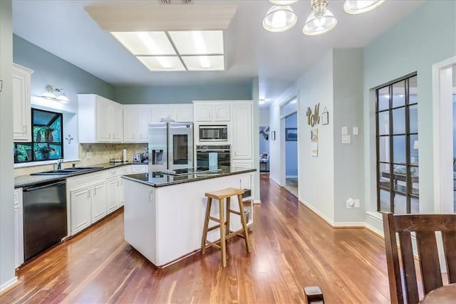 7430 Bourget Dr, Corpus Christi, TX 78413 - kitchen with black appliances, dark countertops, wood finished floors, and tasteful backsplash
