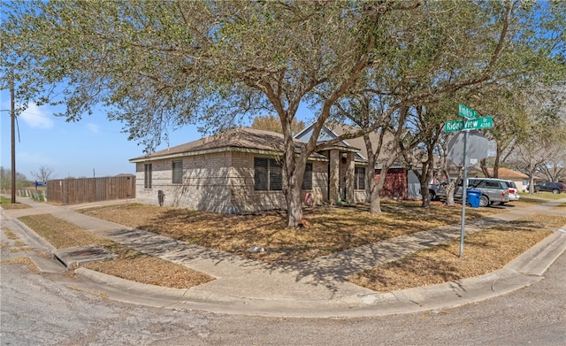 ranch-style home featuring fence and brick siding