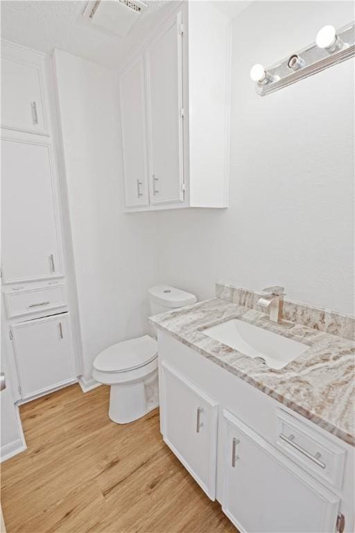 bathroom featuring toilet, vanity, and hardwood / wood-style floors