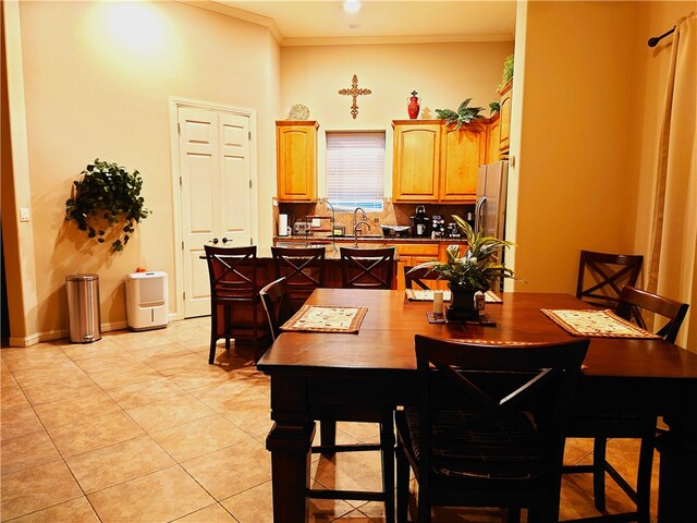 dining room with sink, light tile patterned floors, and crown molding