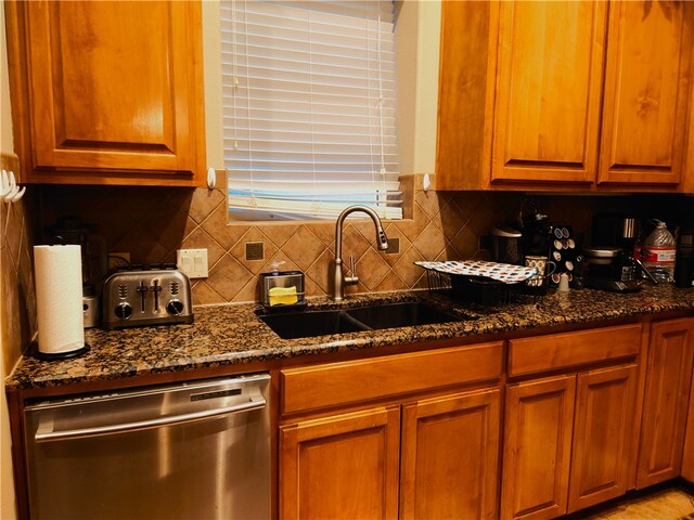 kitchen with dishwasher, sink, backsplash, and dark stone countertops