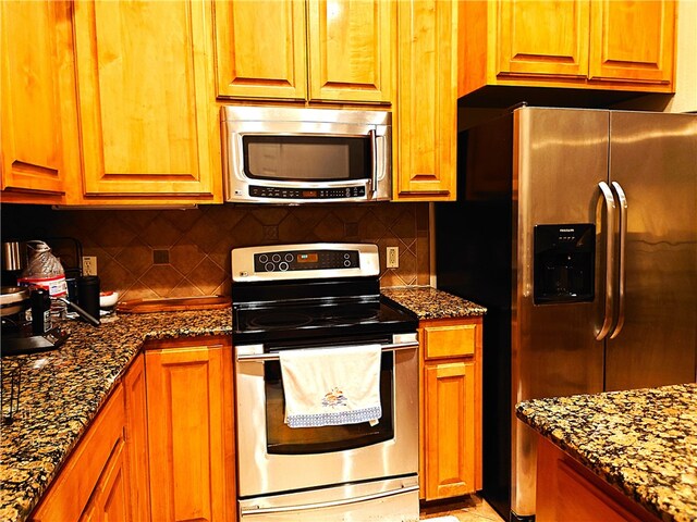 kitchen featuring dark stone counters, appliances with stainless steel finishes, and tasteful backsplash