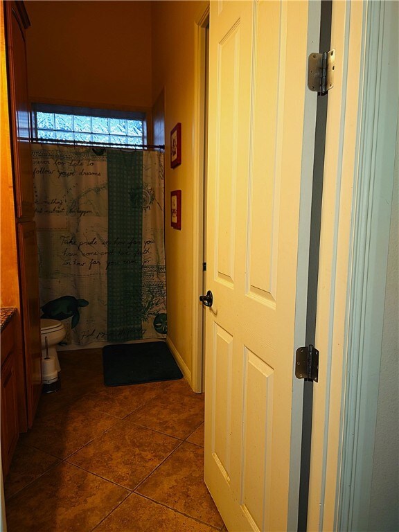 bathroom with walk in shower, toilet, vanity, and tile patterned floors