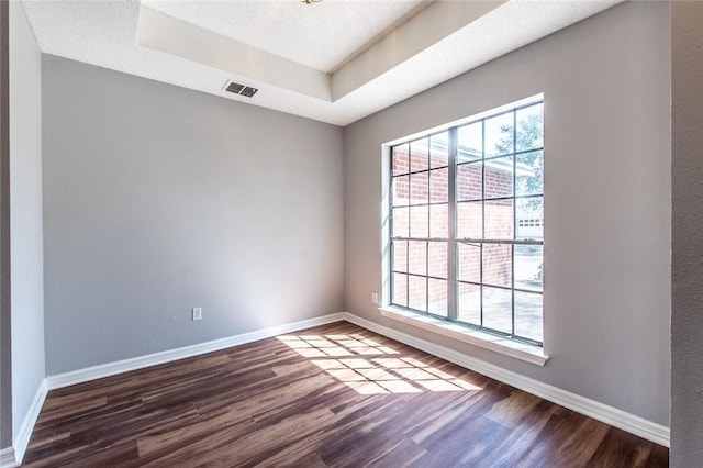 unfurnished room featuring baseboards, a raised ceiling, and wood finished floors