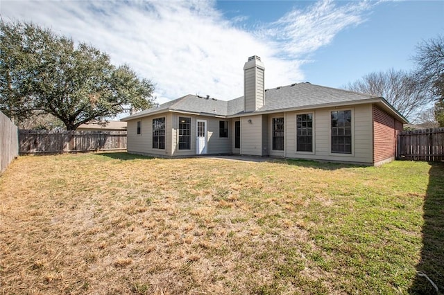 rear view of house featuring a yard, a chimney, and a fenced backyard