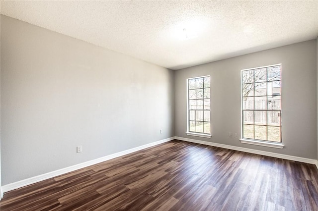 spare room with dark wood-style floors, a textured ceiling, and baseboards