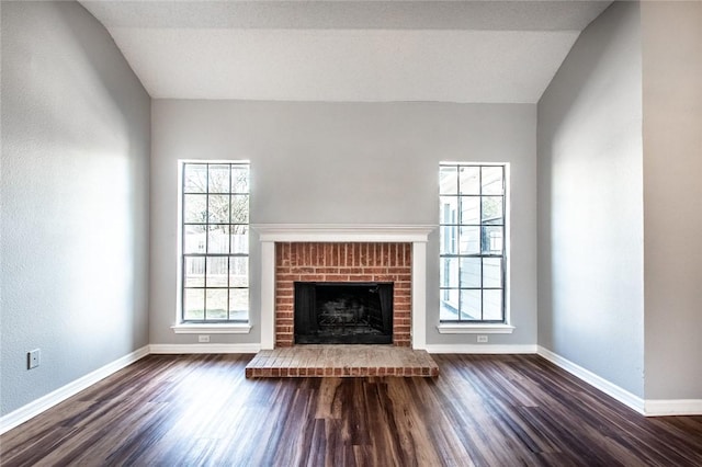 unfurnished living room with dark wood-style floors, vaulted ceiling, a fireplace, and baseboards