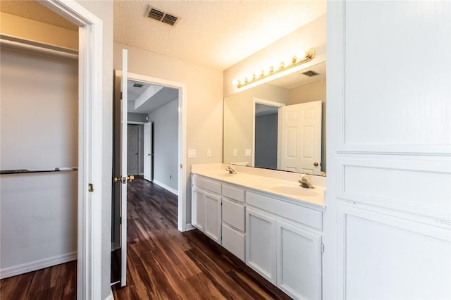 bathroom featuring wood finished floors, a sink, visible vents, and baseboards