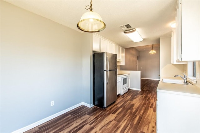 kitchen featuring white range with electric cooktop, light countertops, freestanding refrigerator, white cabinets, and a sink