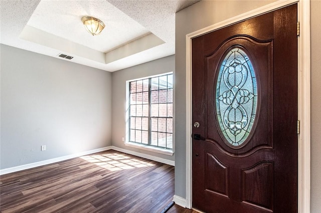 entrance foyer with a textured ceiling, baseboards, a raised ceiling, and dark wood finished floors