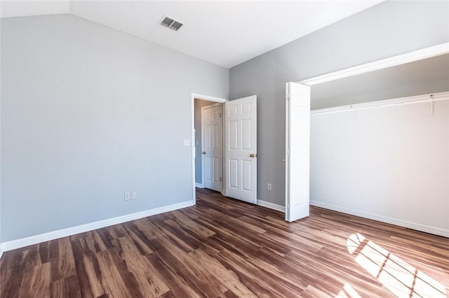 unfurnished bedroom with visible vents, baseboards, dark wood finished floors, vaulted ceiling, and a closet