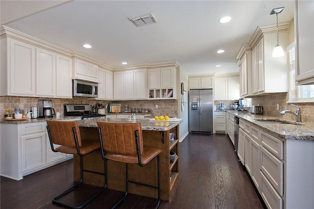 422 Poenisch Dr, Corpus Christi, TX 78412 - kitchen featuring appliances with stainless steel finishes, a center island, light stone counters, a sink, and open shelves
