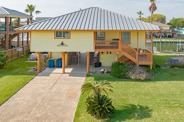 view of front of property with metal roof, concrete driveway, a front yard, and a water view