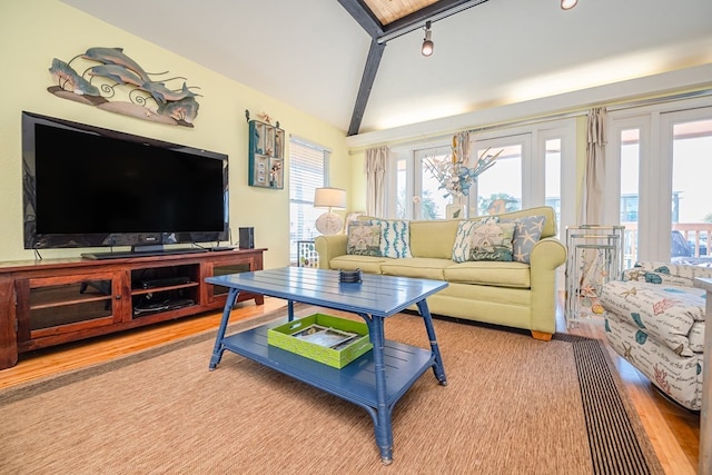 living room featuring vaulted ceiling with beams, rail lighting, and light wood-style flooring