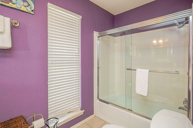 full bath featuring tile patterned flooring, toilet, and bath / shower combo with glass door