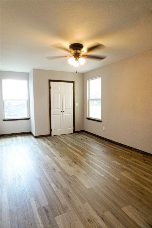 unfurnished bedroom with hardwood / wood-style floors, ceiling fan, and multiple windows