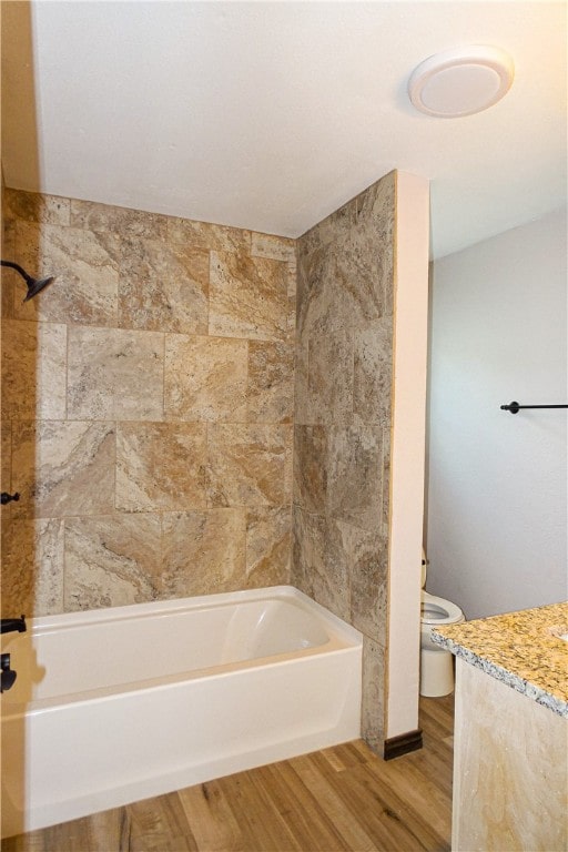 full bathroom with hardwood / wood-style floors, tiled shower / bath, toilet, and vanity