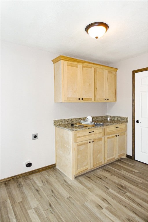 kitchen featuring dark stone counters, light brown cabinets, and light hardwood / wood-style floors