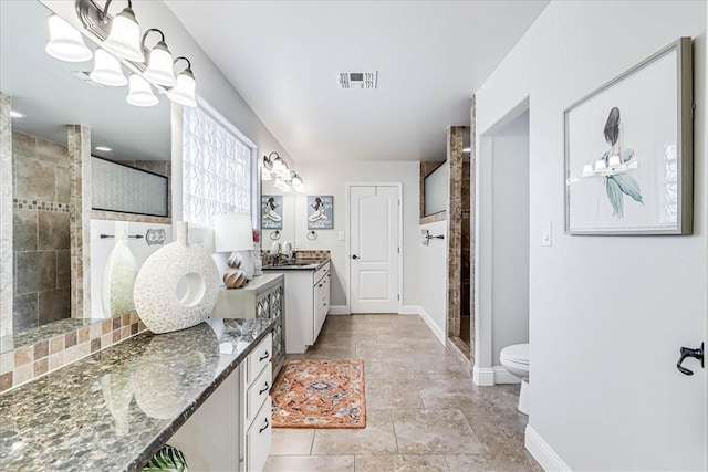 bathroom featuring a tile shower, vanity, and toilet