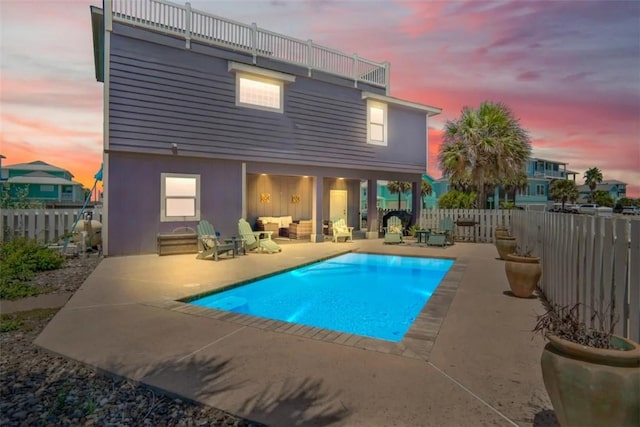 pool at dusk featuring a patio area and an outdoor living space