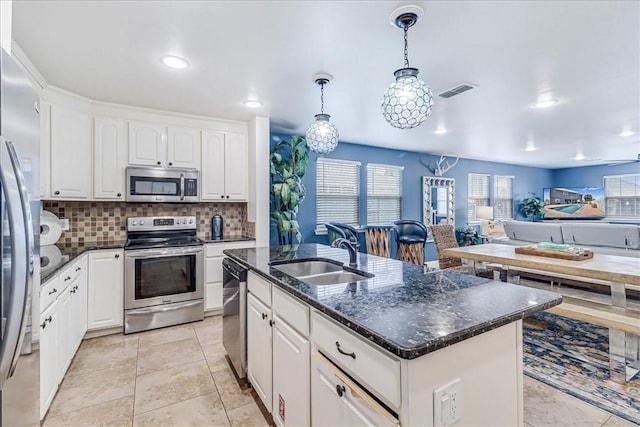 kitchen featuring stainless steel appliances, white cabinetry, a center island with sink, and sink