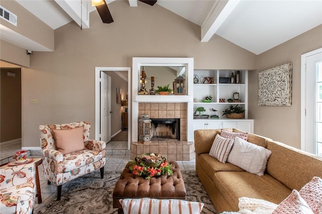 living room featuring ceiling fan, beamed ceiling, a tiled fireplace, tile patterned flooring, and visible vents