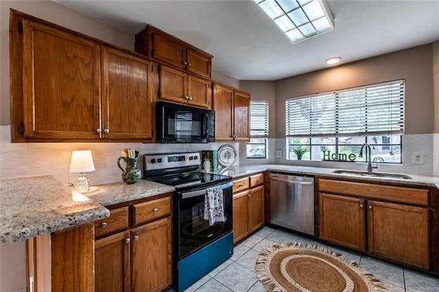 kitchen featuring stainless steel appliances, backsplash, a sink, and brown cabinets